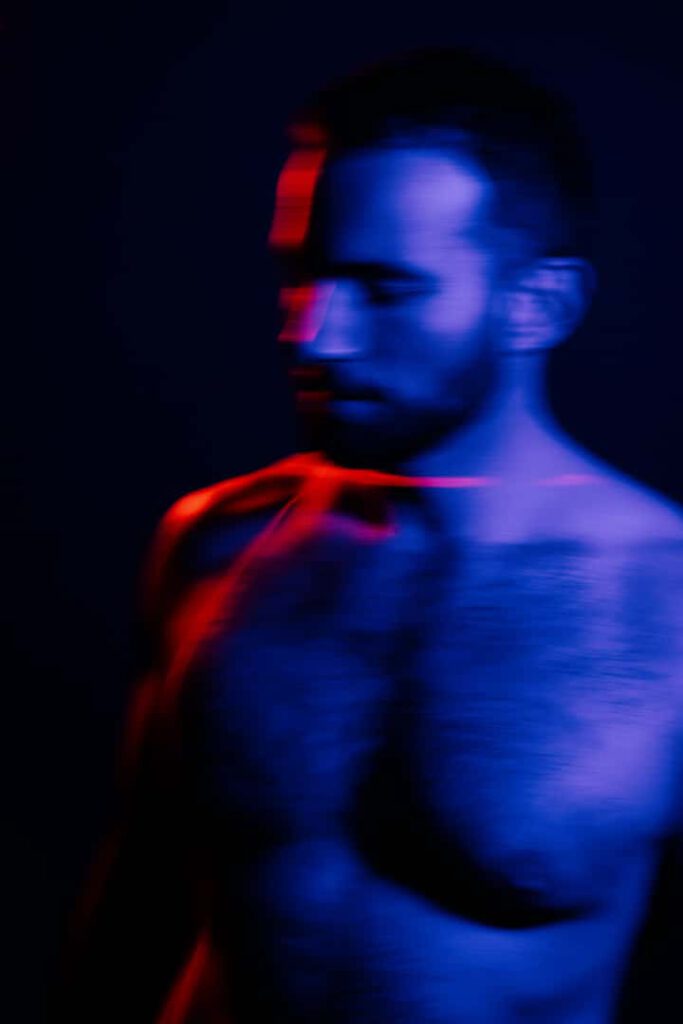 Mann im farbigen Licht zwischen blau und rot.